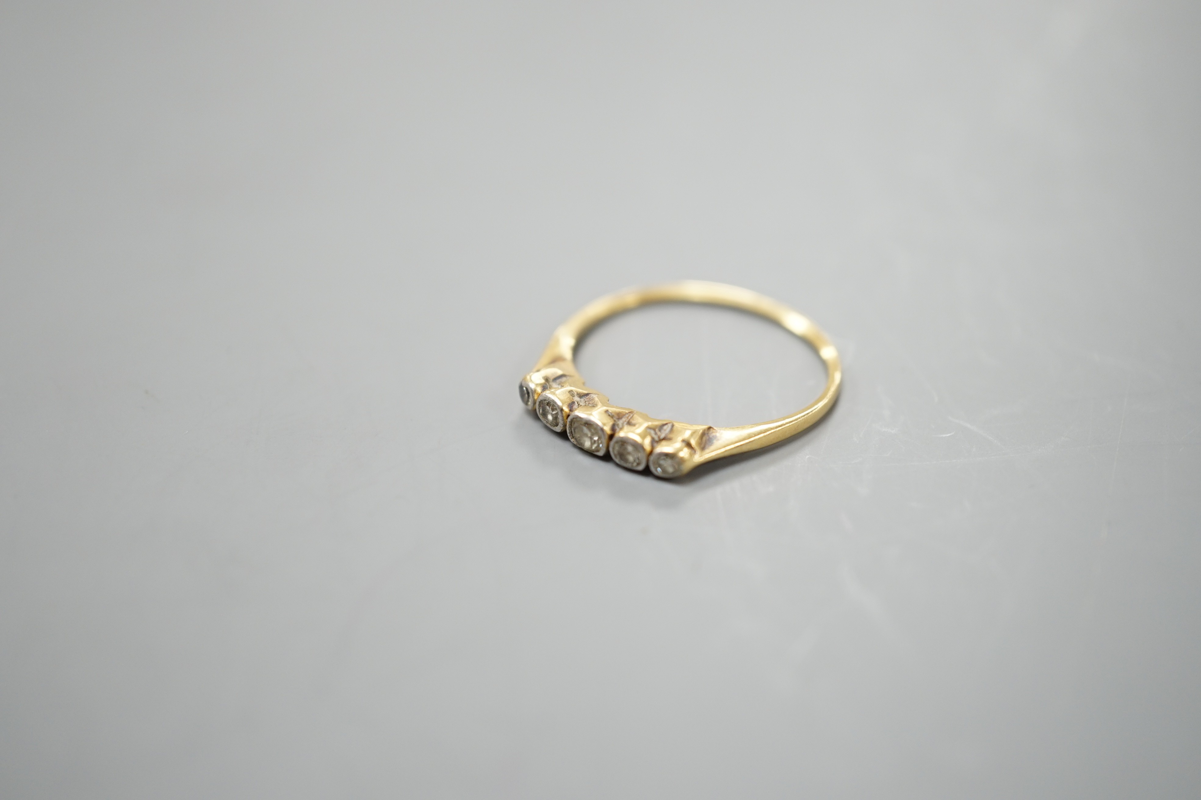 A yellow metal and graduated collet set five stone diamond half hoop ring, size O, gross weight 1.7 grams.
